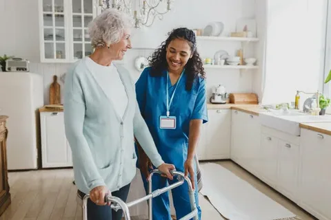 Home care caregiver assisting an elderly woman using a walker
